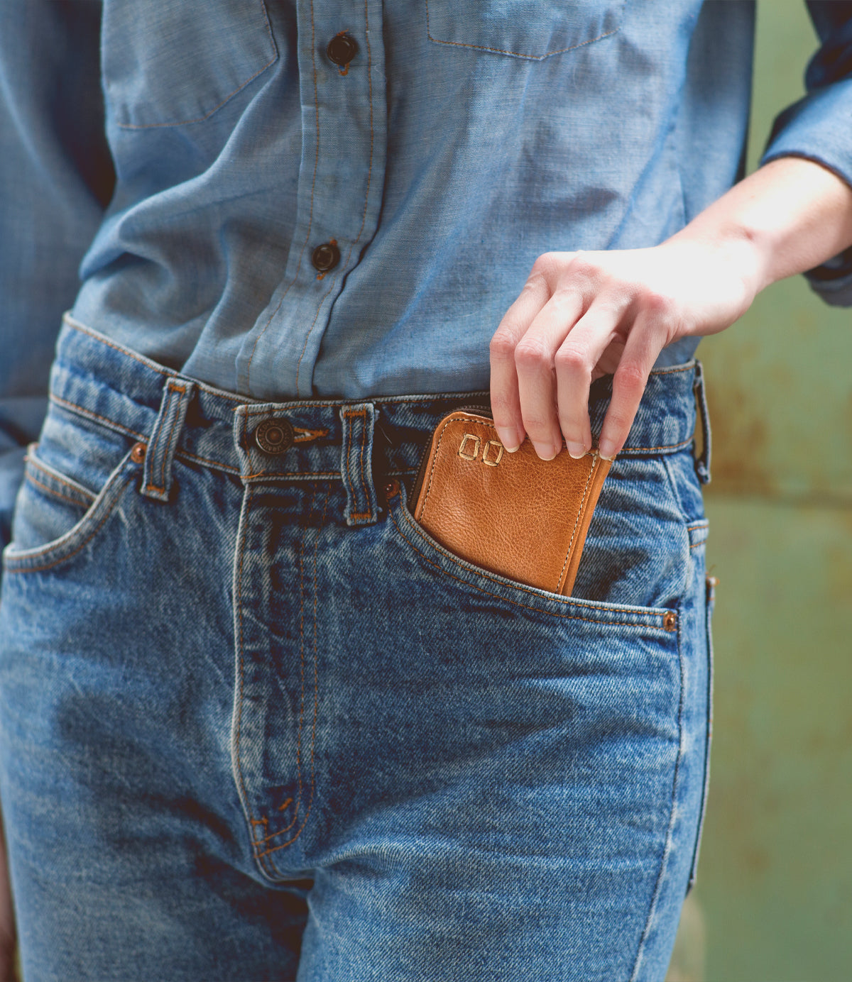 A woman is carrying a Bed Stu Carrie compact wallet in her jeans pocket, containing her necessities.
