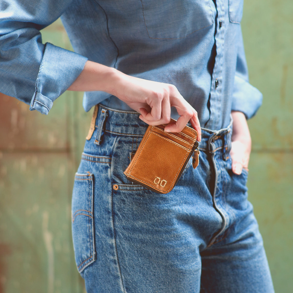 A woman is holding a Bed Stu Carrie wallet in her jeans.