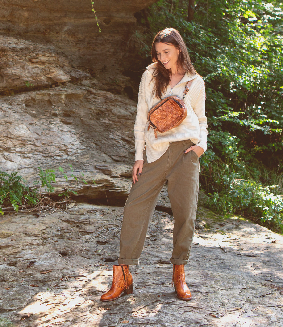 A woman is standing on a rock wearing brown Celestine boots by Bed Stu with a western-inspired design.