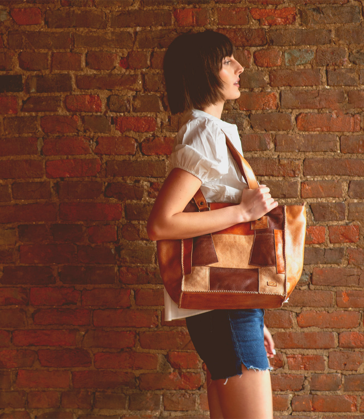 A woman showcasing a beautiful Bed Stu Celindra LTC II tote bag with a spacious interior.