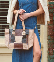 A woman in a denim dress holding a Bed Stu Celindra LTC II tote bag.