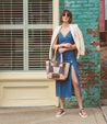 A woman in a vibrant blue dress holding a Bed Stu Celindra LTC II tote bag with a spacious interior.