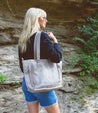 A woman, Bed Stu, is holding a beige tote bag.