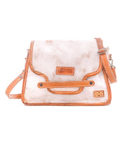 The Bed Stu Ceremonious is a beige and brown preppy bag featuring a front flap, adjustable strap, and visible stitching. Displayed on a white background, this handbag keeps essentials organized in style.