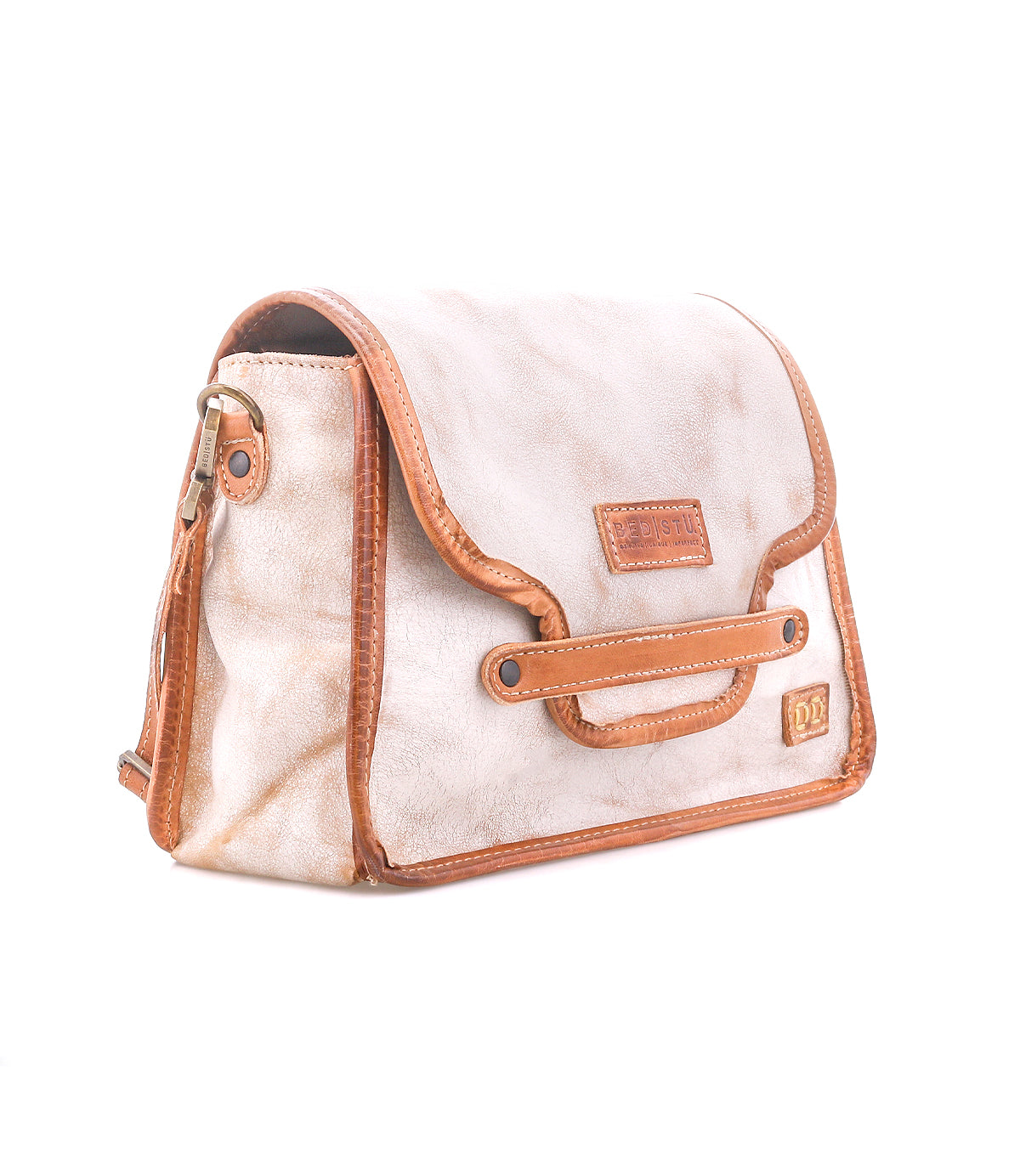 The Bed Stu Ceremonious is a preppy beige and brown leather flap-top bag with a shoulder strap, side buckle, and stitched details, designed for organized handbag style against a white background.