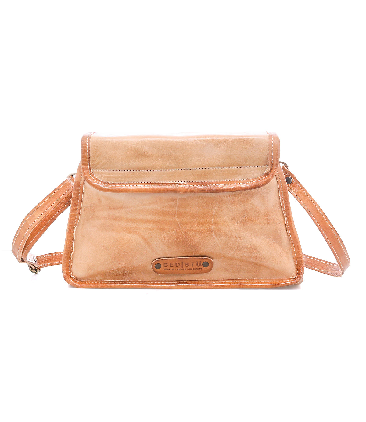 The Ceremonious by Bed Stu is a light brown leather flap-top bag with visible stitching, an adjustable strap, and logo on the front—a stylish, organized handbag ideal for everyday use.