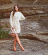A woman in a cream Ceretti sweater dress and Bed Stu limited-edition brown boots is posing for a photo.