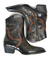 The Bed Stu Chamise boots—black leather western style with brown and tan stitching, stylish inlays, side zippers, snip toe, and stud accents—are shown arranged with one boot on its side and the other upright.