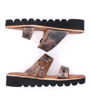 Two Chow distressed bronze flat sandals by Bed Stu, featuring scalloped black soles and cushioned footbeds for comfort, are positioned side by side with one facing left and the other right.