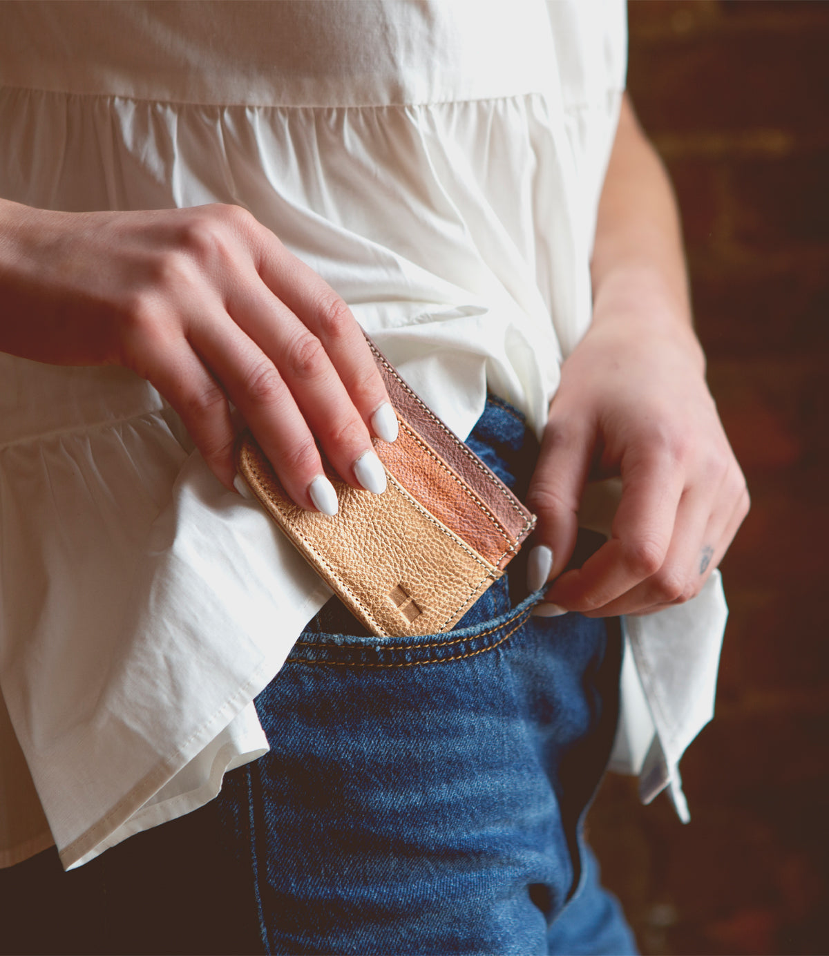 A person putting a Bed Stu Chuck card wallet in their pocket.