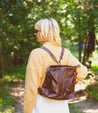 A woman with a Bed Stu Cirdan leather backpack walking through the woods.