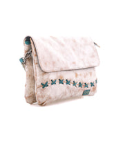 The Cleo by Bed Stu is a light beige leather crossbody bag with an adjustable strap, flap closure, teal X-shaped stitching, and a small front logo patch.