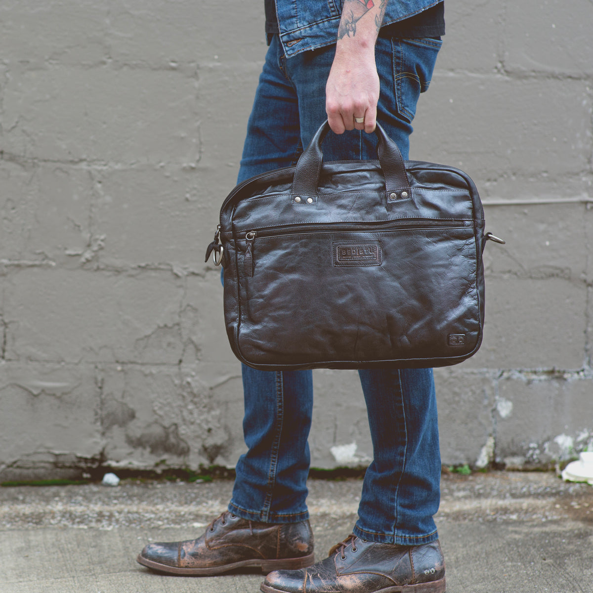 A man holding a black vegetable-tanned leather Bed Stu Conclusion briefcase.