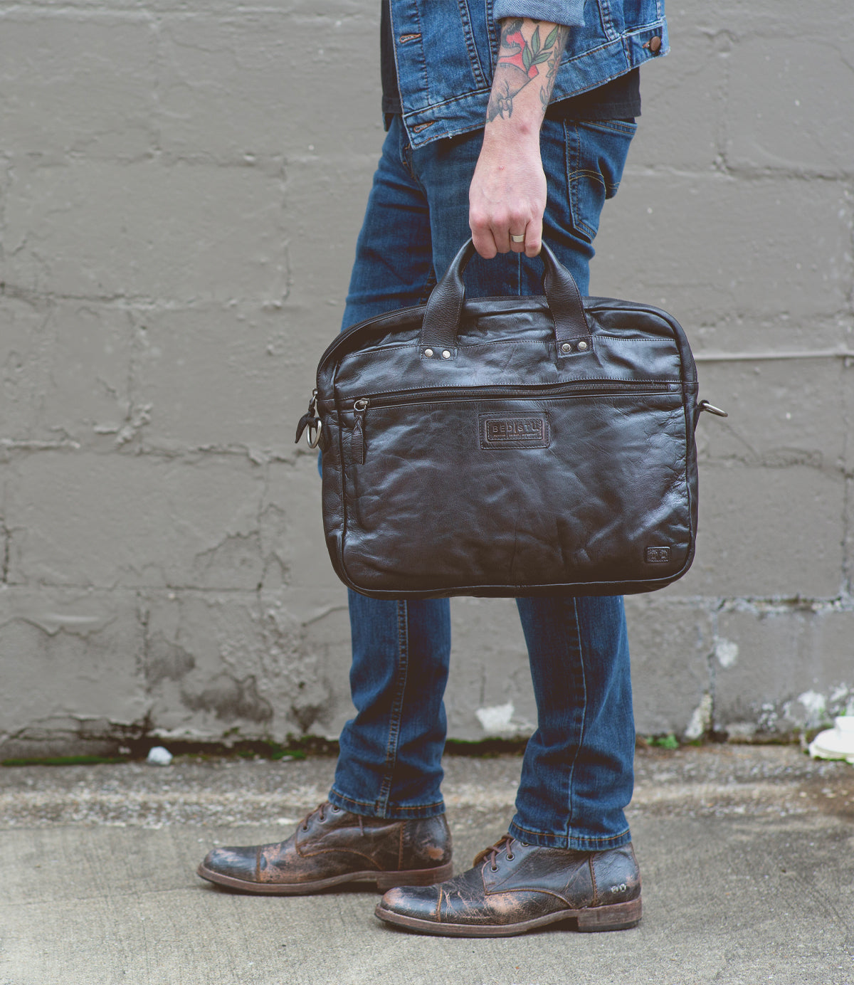 A man holding a black vegetable-tanned leather Bed Stu Conclusion briefcase.