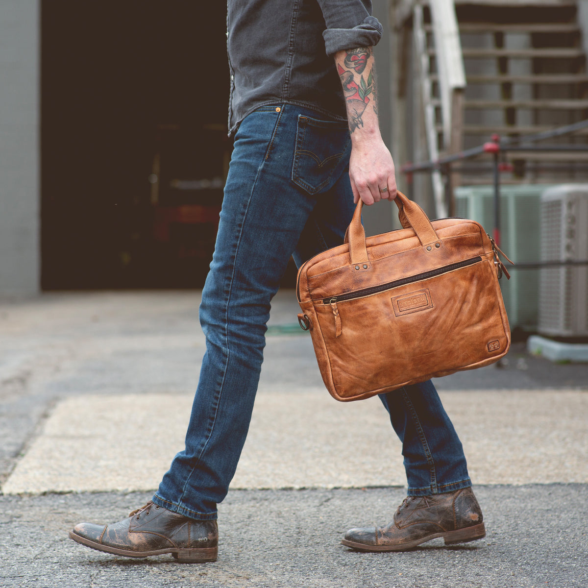 A man carrying a Bed Stu Conclusion laptop bag.