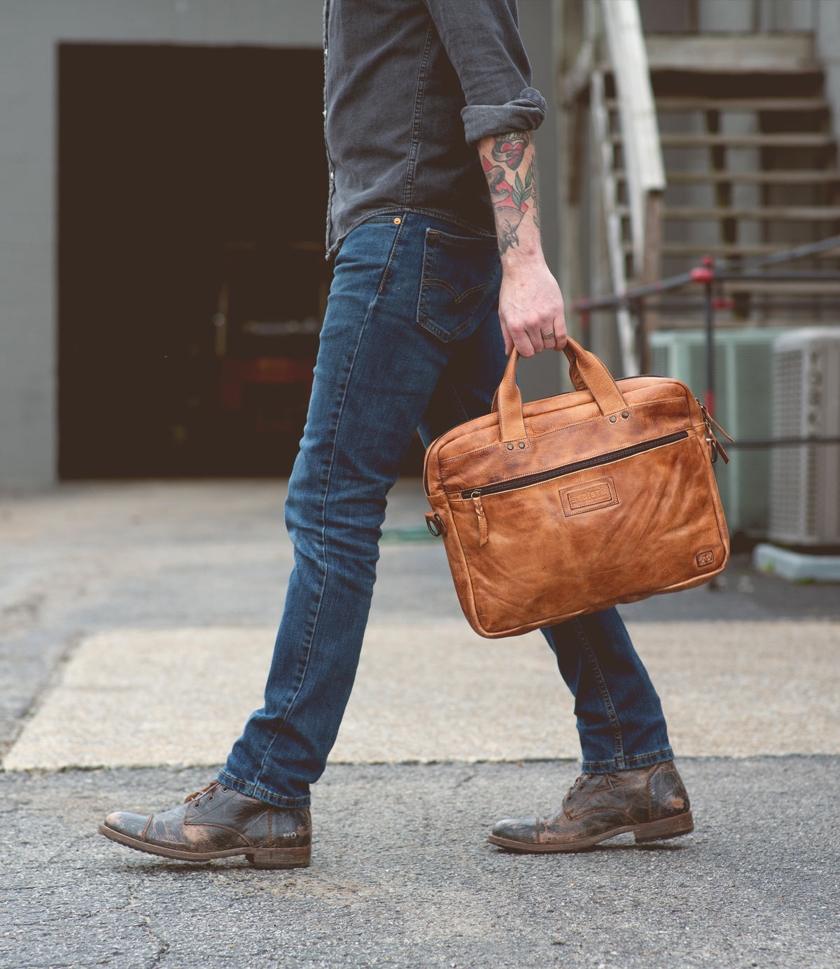 A man carrying a Bed Stu Conclusion laptop bag.