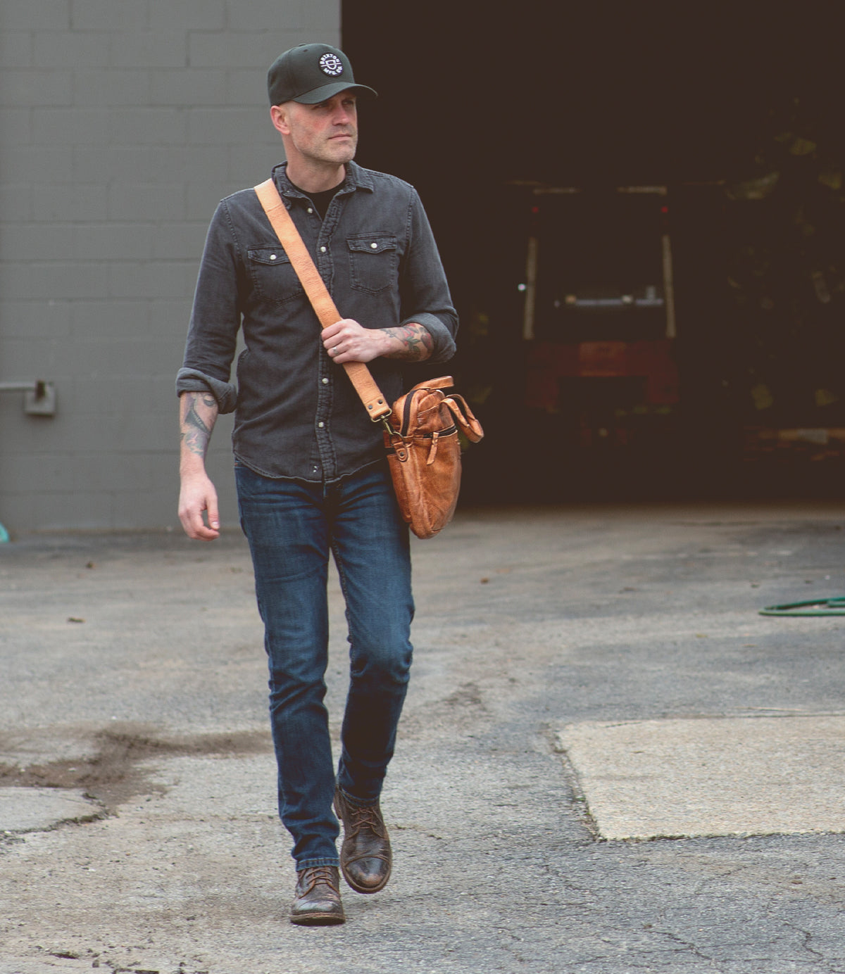 A man walking with a Bed Stu Conclusion laptop bag.