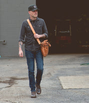 A man walking with a Bed Stu Conclusion laptop bag.