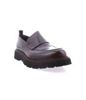 The Costruito penny loafer from Bed Stu, crafted in Italy, features brown leather and artisanal charm with a thick black sole. It is showcased from the front angle on a white background.