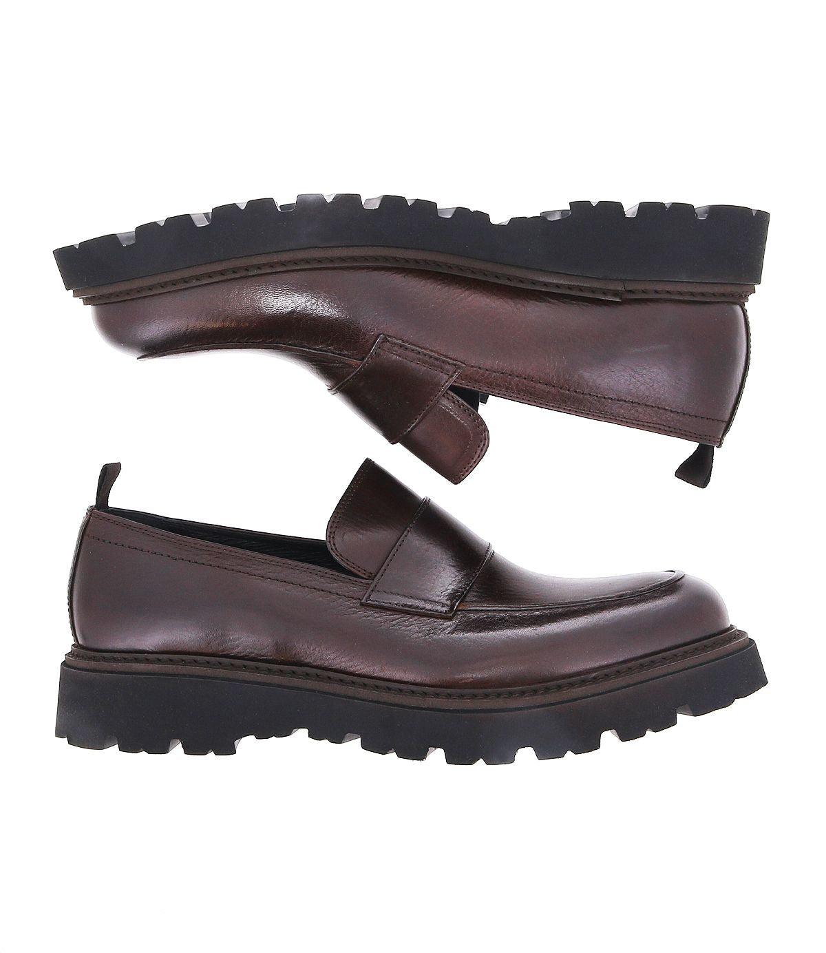 The Costruito penny loafers by Bed Stu, crafted in Italy from brown leather and boasting thick black rubber soles, are displayed from a side view. These shoes combine artisanal charm with a sophisticated design, ideal for those who value fine craftsmanship.