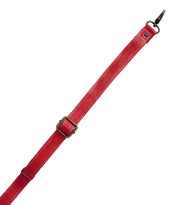 The Bed Stu Crossbody Strap is a red adjustable leather strap with a brass buckle and metal clasp, ideal for Bed Stu bags or as a crossbody accessory, shown on a white background.
