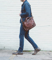 A man is walking with a Depp briefcase, emblematic of meticulous organization by Bed Stu.