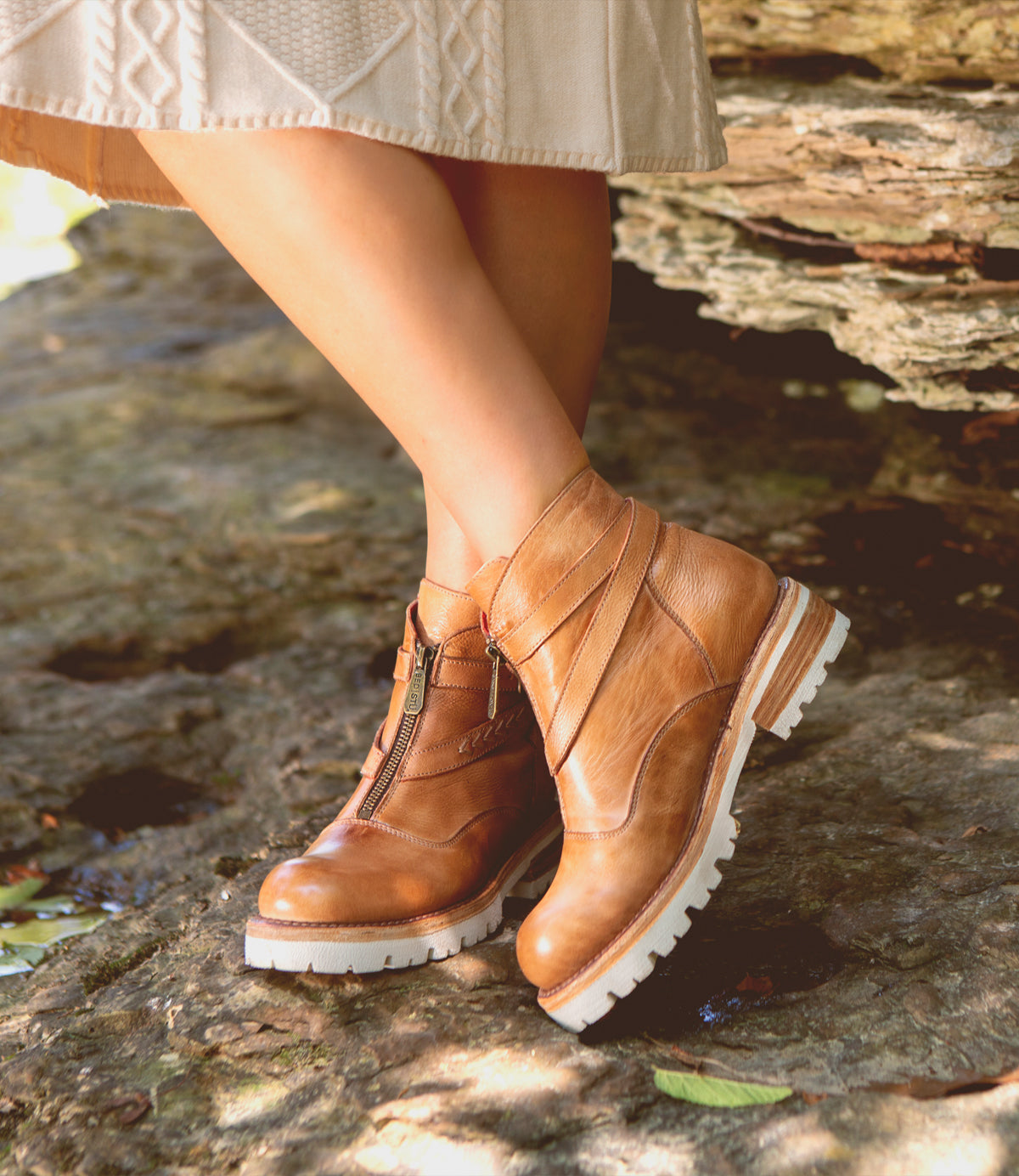A woman wearing lightweight tan leather Bed Stu Dessa ankle boots standing on a rock.
