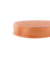 A tan Bed Stu Dreampath EM leather circular tray with embossed floral patterns, inspired by a genuine leather belt, shown against a white background.