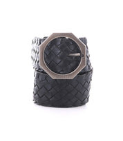 The Bed Stu Dreamweaver is a black woven leather belt with vintage allure, featuring a large octagonal silver buckle, rolled up and displayed on a white background.