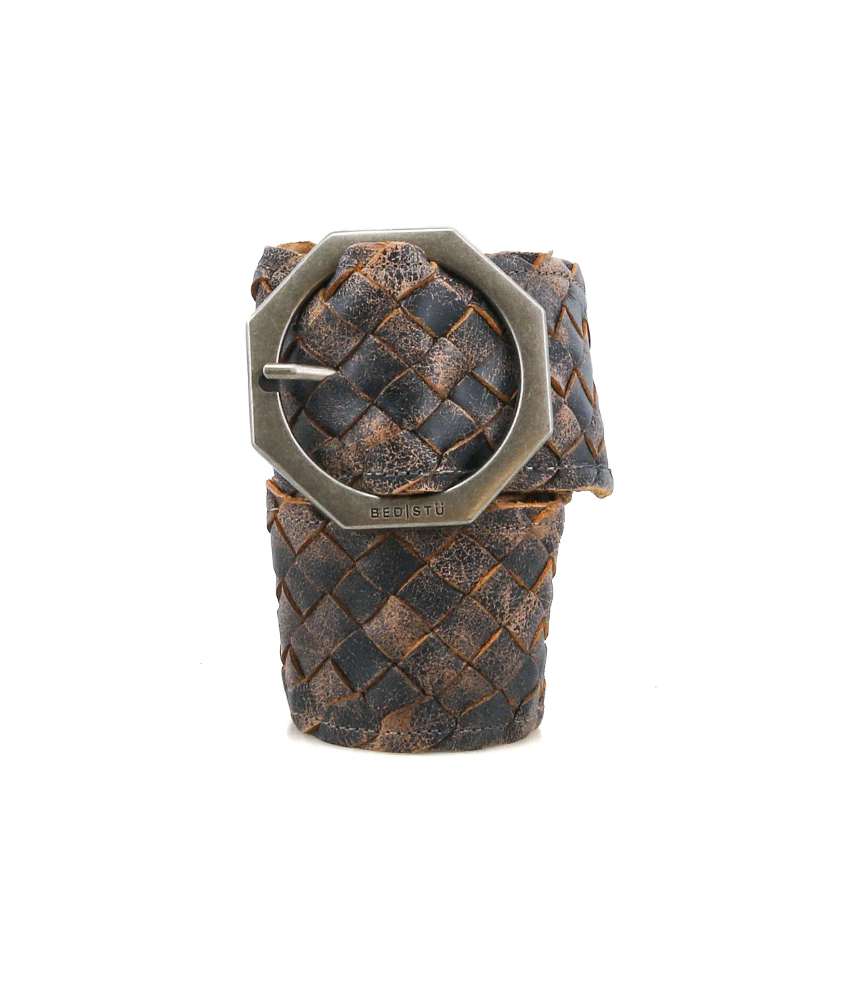 The Bed Stu Dreamweaver is a brown and black vintage boho belt, woven from leather with a large hexagonal metal buckle, shown rolled up and upright against a white background.