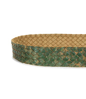 A close-up of Bed Stu's Dreamweaver belt showcases its green and beige woven leather, braided pattern, and bold metal buckle.