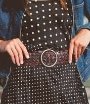 A person wears a black and white polka dot dress, the Bed Stu Dreamweaver wide brown woven belt with a brass-tone buckle, and a blue denim jacket.