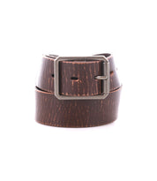 The Drifter belt by Bed Stu, featuring brown leather and a silver metal buckle, exudes dapper appeal as it is rolled up against a white background.