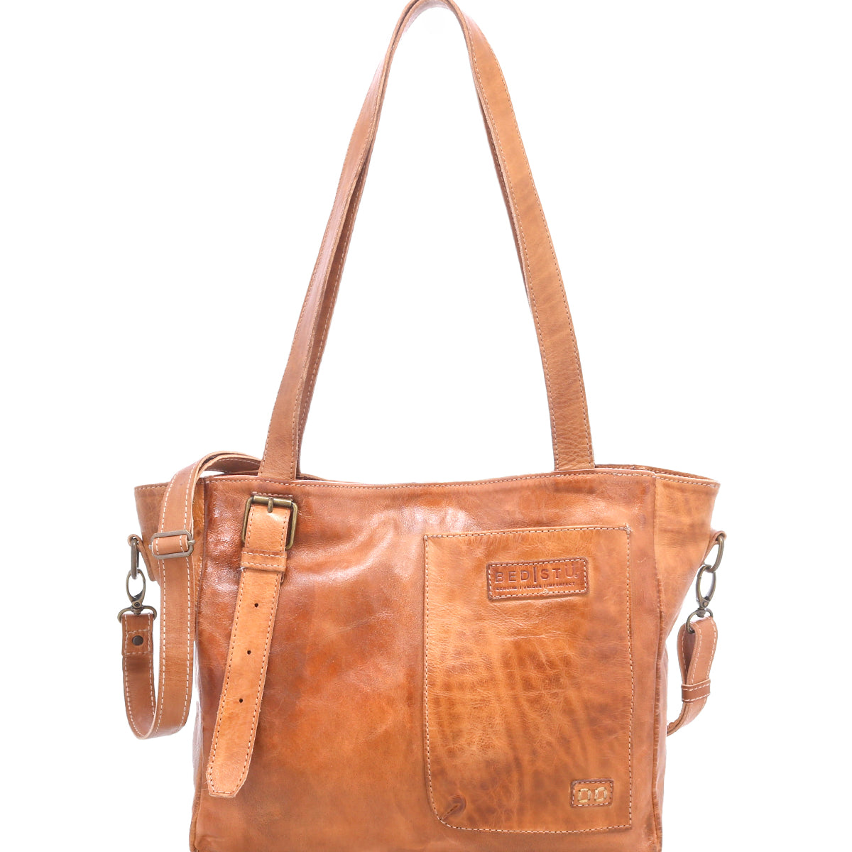 The Bed Stu Explicit LTC is a light brown seasoned leather bag with two top handles, an adjustable strap, and a front patch pocket with stitched details plus a small embossed logo, adding rustic appeal.