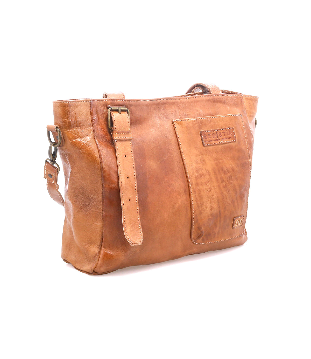 The Bed Stu Explicit LTC is a light brown seasoned leather bag with an adjustable strap, front pocket, visible stitching, and rectangular embossing. This utility bag has a rustic appeal and is shown against a white background.