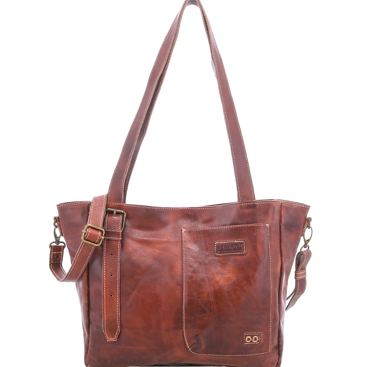 The Bed Stu Explicit LTC is a brown leather shoulder bag with two handles, an adjustable strap, visible stitching, a front pocket, and a small rectangular logo patch for rustic appeal and versatile utility.