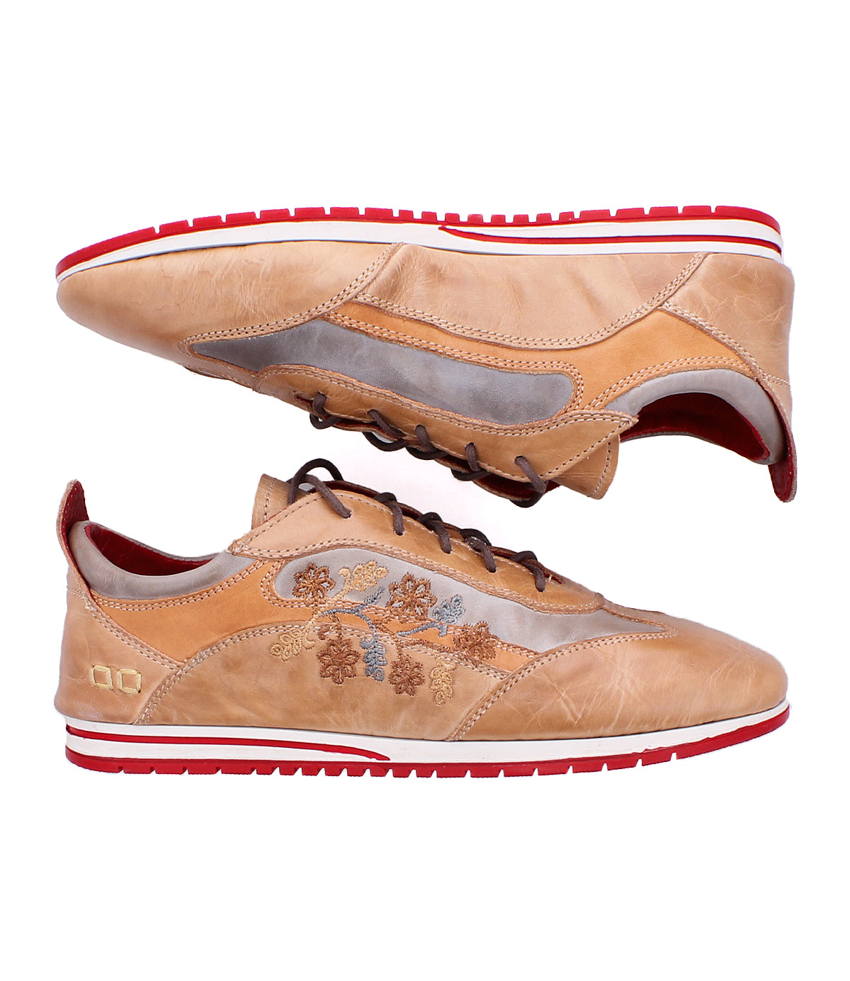 Introducing Extravagant by Bed|Stü—a pair of tan leather sneakers with a lace-up silhouette, accented by brown laces, vibrant red and white soles, and delicate floral embroidery along the sides. The artfully worn-in leather lends a laid-back, stylish vibe that’s ideal for everyday wear. Shown here in both side and top views.