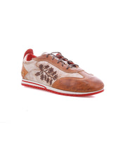 Introducing Extravagant by Bed|Stü: a brown leather sneaker adorned with floral embroidery, distinctive red accents, a crisp white midsole, and a bold red outsole. This lace-up silhouette is crafted for everyday wear and is displayed at an angle against a white background.
