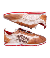 The Bed|Stü Extravagant sneakers feature a classic lace-up silhouette crafted from softly worn-in leather, showcasing brown and beige tones with red soles, brown laces, and floral embroidery on the side—perfect for everyday wear and displayed side by side.