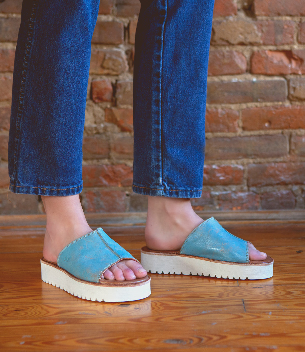 A person wearing stylish blue Fairlee II leather slide sandals from Bed Stu.