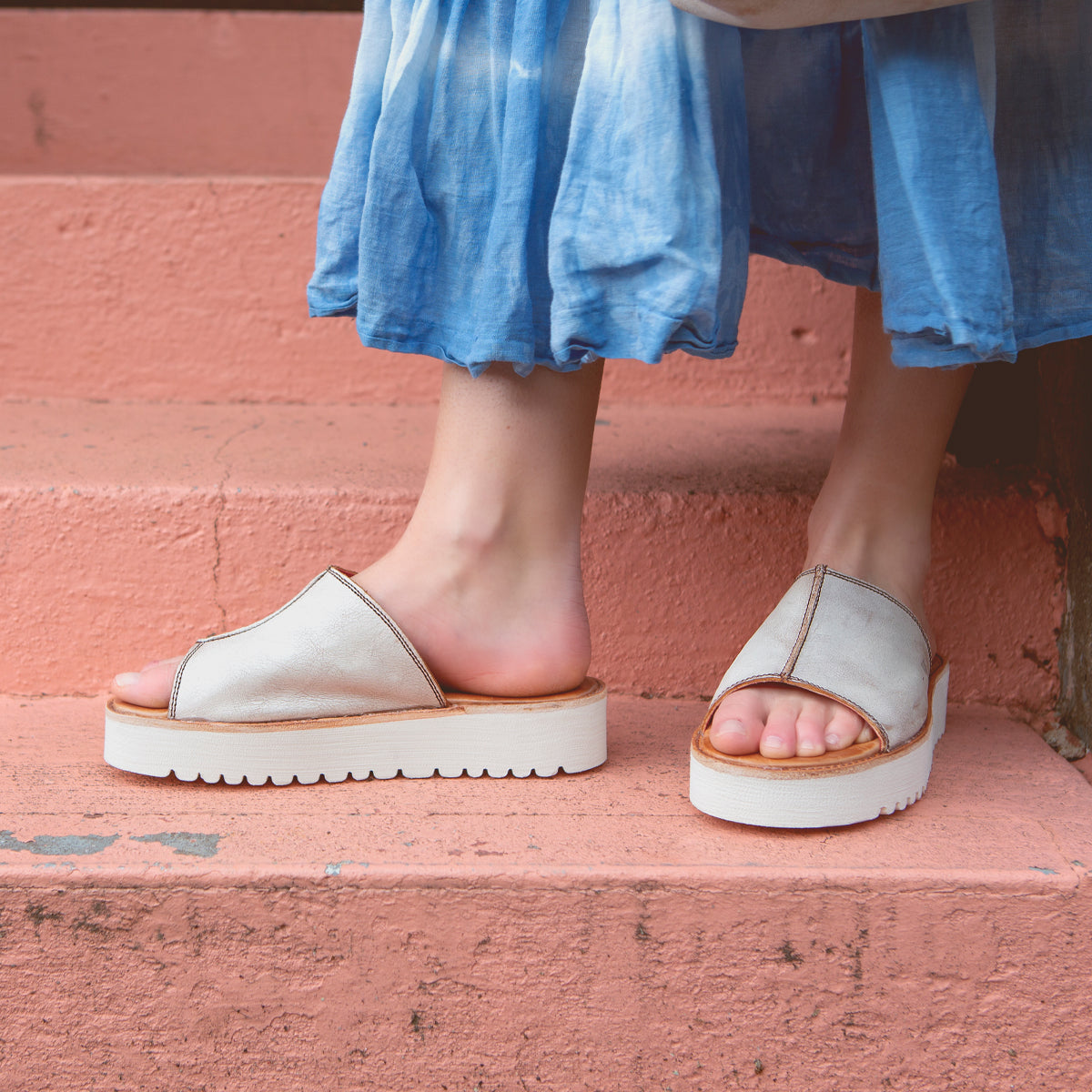 A person wearing Fairlee II leather slide sandals from Bed Stu and standing on steps, exuding both comfort and style.