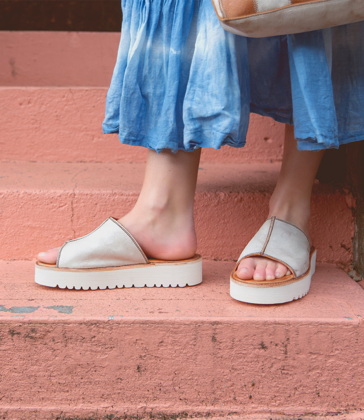 A person wearing Fairlee II leather slide sandals from Bed Stu and standing on steps, exuding both comfort and style.