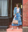 A stylish woman in a denim jacket and a skirt, comfortably wearing Bed Stu Fairlee II leather slide sandals.