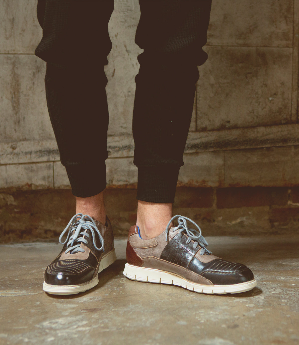 A man with distinct character wearing a pair of Bed Stu Fairman low-top leather sneakers and black pants.