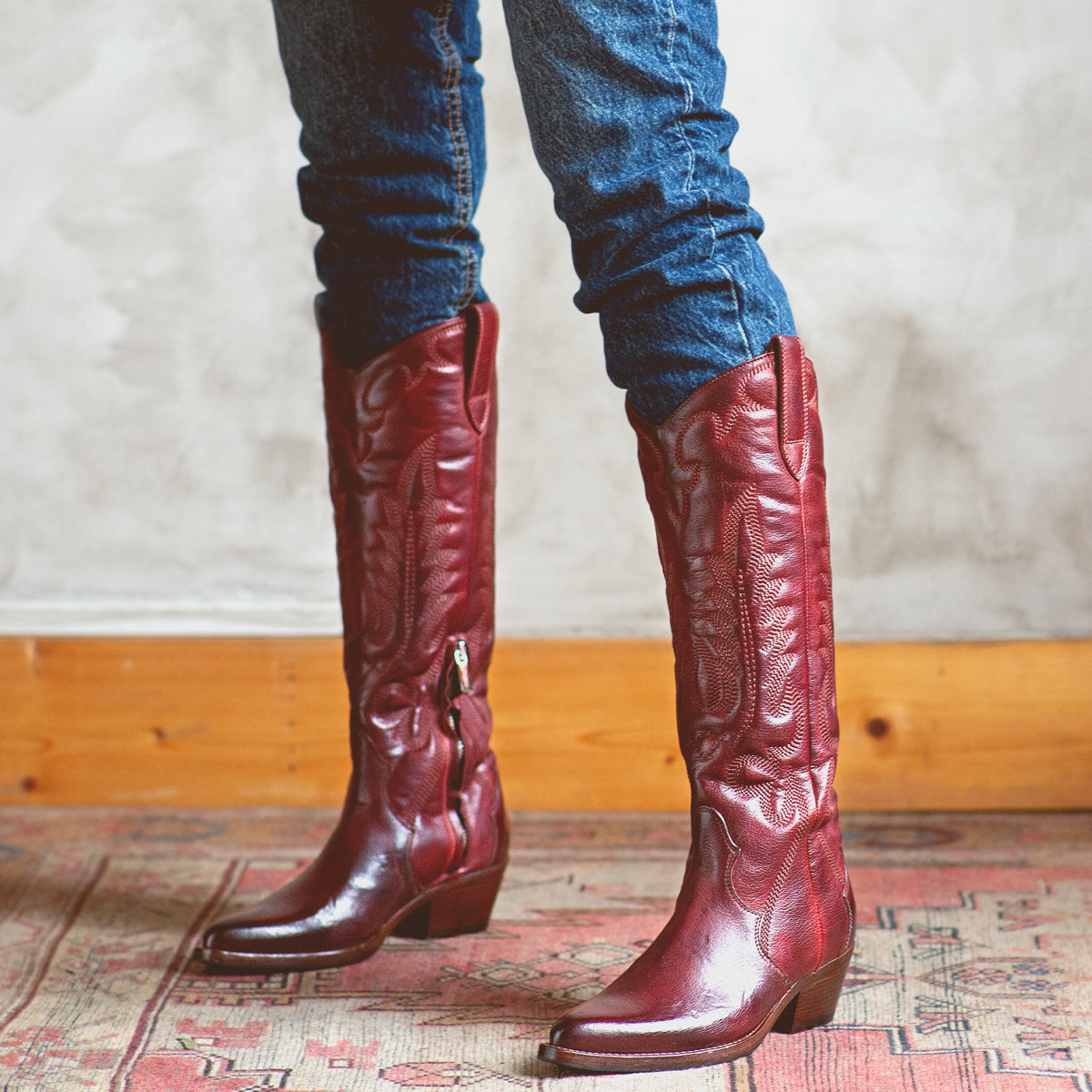 A woman wearing a pair of Bed Stu Finito burgundy distressed leather cowboy boots.