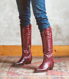 A woman wearing a pair of Bed Stu Finito burgundy distressed leather cowboy boots.