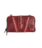 A Bed Stu Flee, a leather clutch in red, features metal stud embellishments, a central strap, and a secure zip closure.