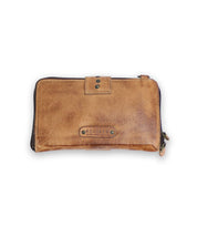 The Flee wallet by Bed Stu is crafted in brown leather, adorned with metal studs, and has the brand name embossed on the front. It features a secure zip closure and snap fastening.