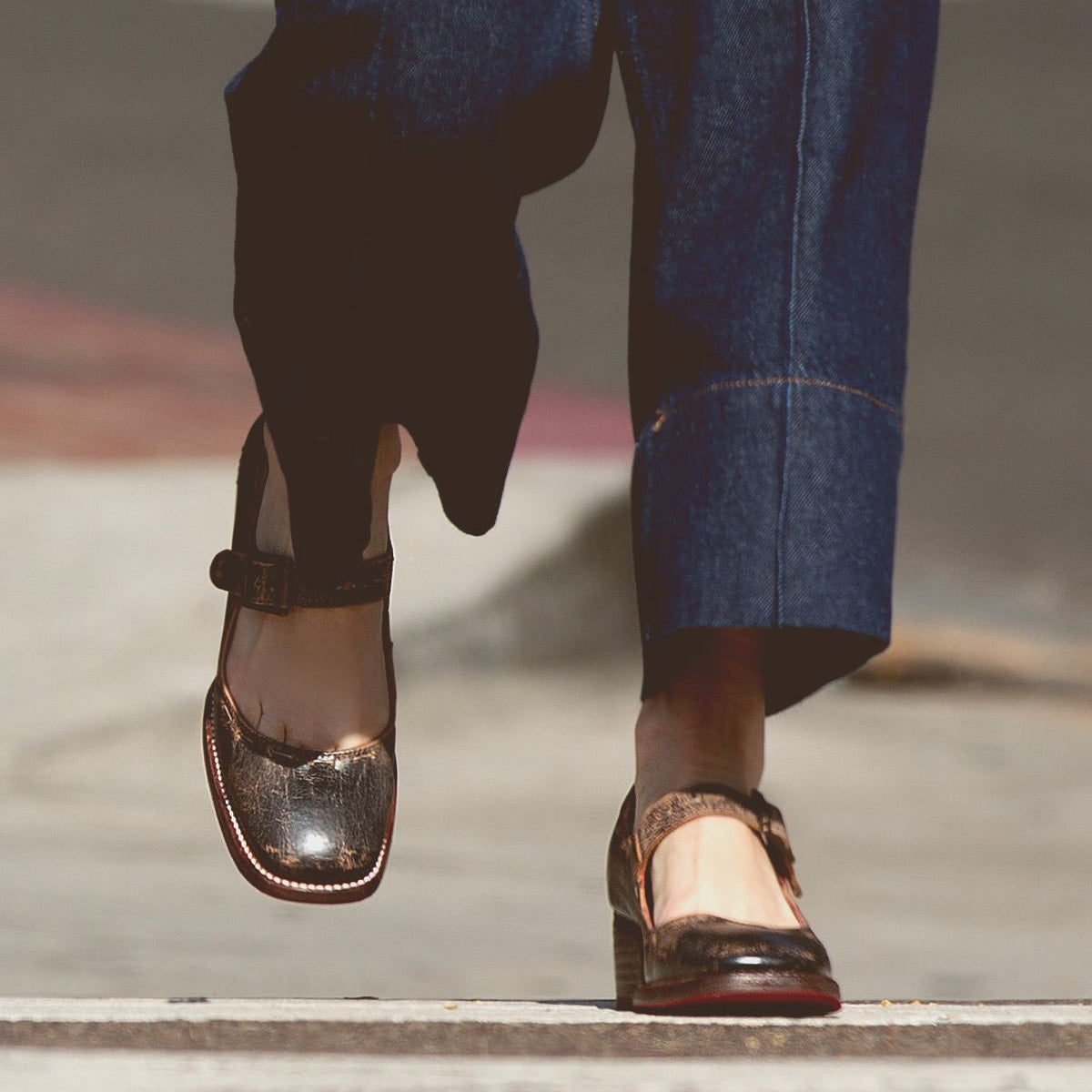 Person wearing Bed Stu's Forefront leather Mary Jane shoes with a comfortable heel and wide-leg denim pants, walking across the pedestrian crossing.