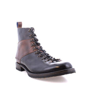The Frenzy by Bed Stu is a black and brown leather ankle boot, intricately laced and perfect for adventure. Built with durable Goodyear welt construction and a low heel, this men's hiking boot makes a striking impression against a white background.